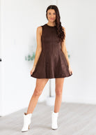 Woman wearing a brown dress with white boots in a minimalistic setting