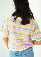 Person wearing a colorful striped sweater with a plain background
