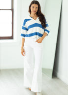 Woman wearing a blue and white striped sweater and white pants in a bright room.