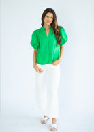 Woman wearing a green blouse and white pants on a white background