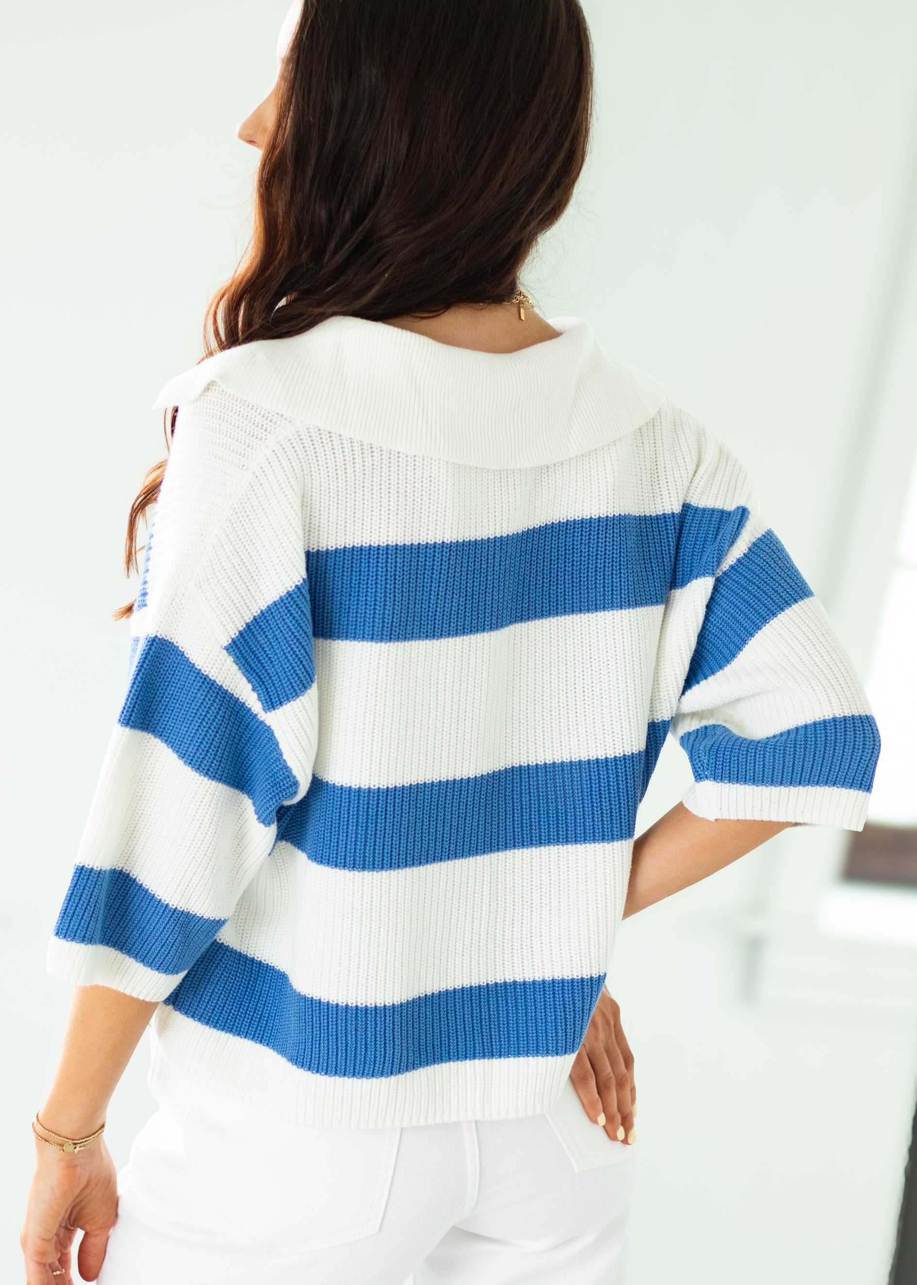 Woman wearing a blue and white striped sweater against a plain background