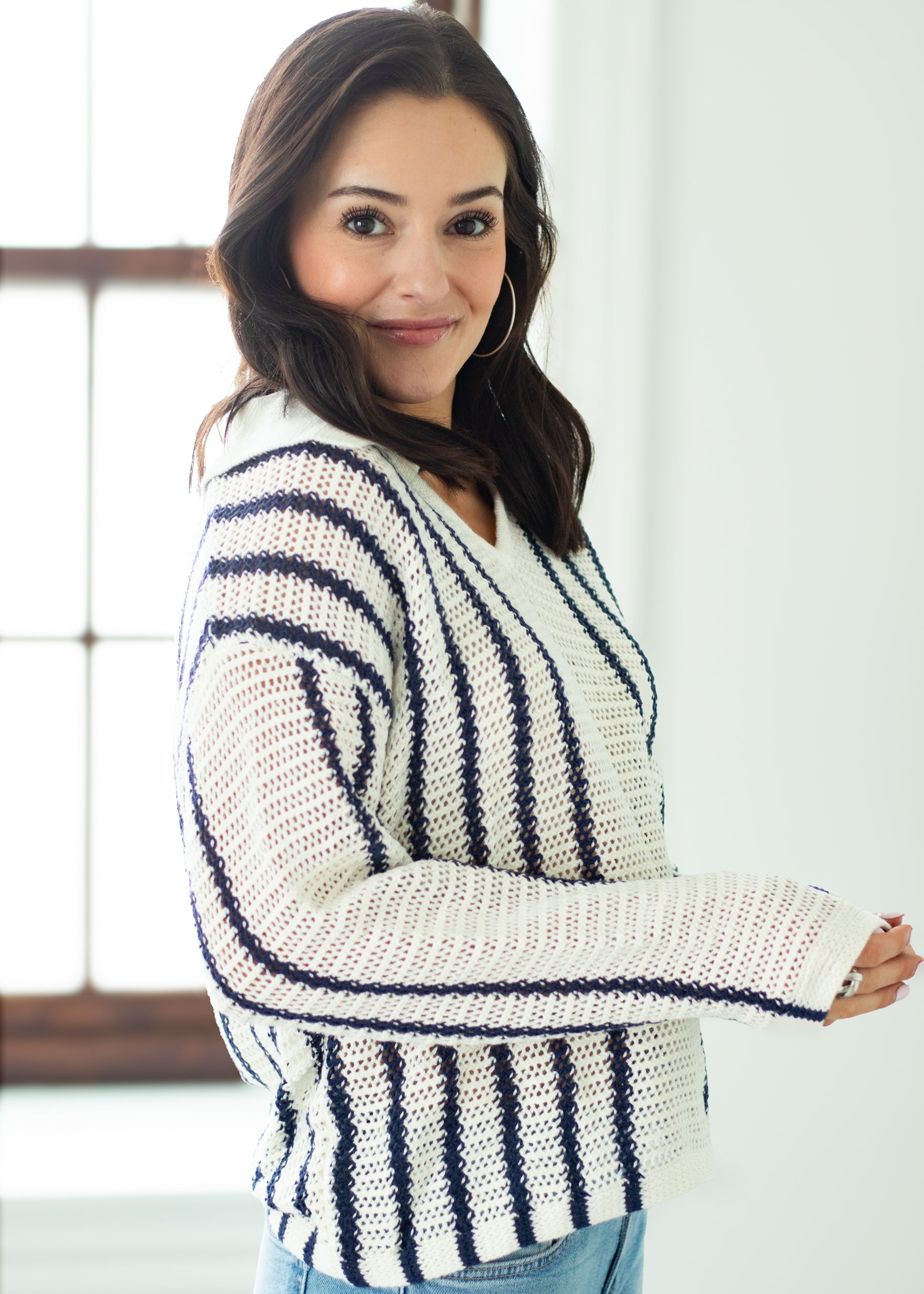 Woman wearing a white and navy striped cardigan indoors