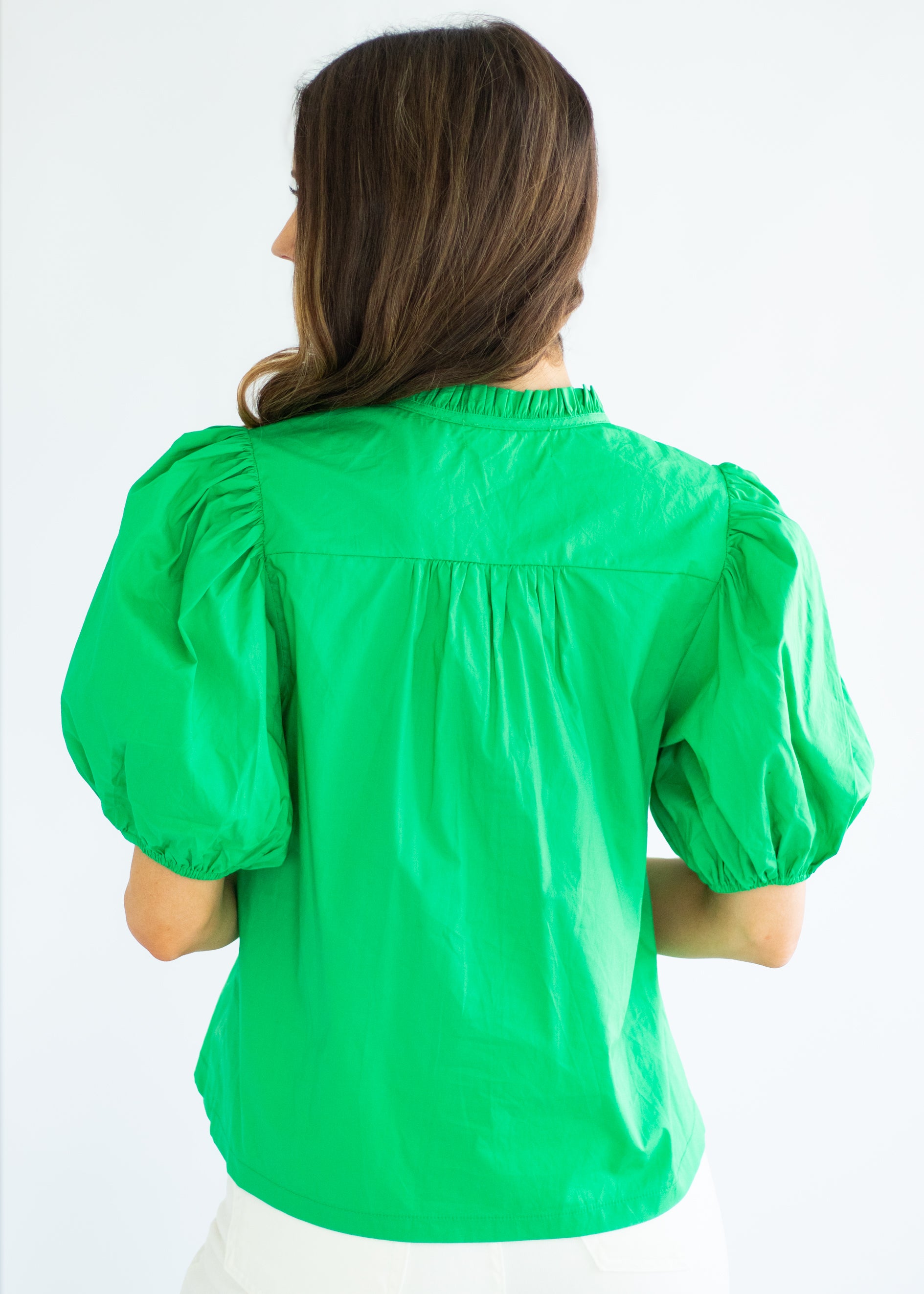 Woman wearing a green blouse with puffed sleeves on a white background