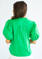 Woman wearing a green blouse with puffed sleeves on a white background