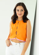Woman wearing an orange sleeveless top with a white background