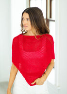 Woman wearing a red knitted poncho against a white background