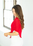 Woman wearing a red knitted sweater in a bright room