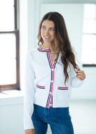 Woman wearing a white cardigan with red and blue accents in an indoor setting
