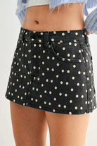 Black polka dot skirt worn by a person on a plain background