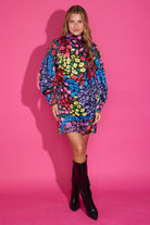 Woman wearing a colorful floral dress against a pink background