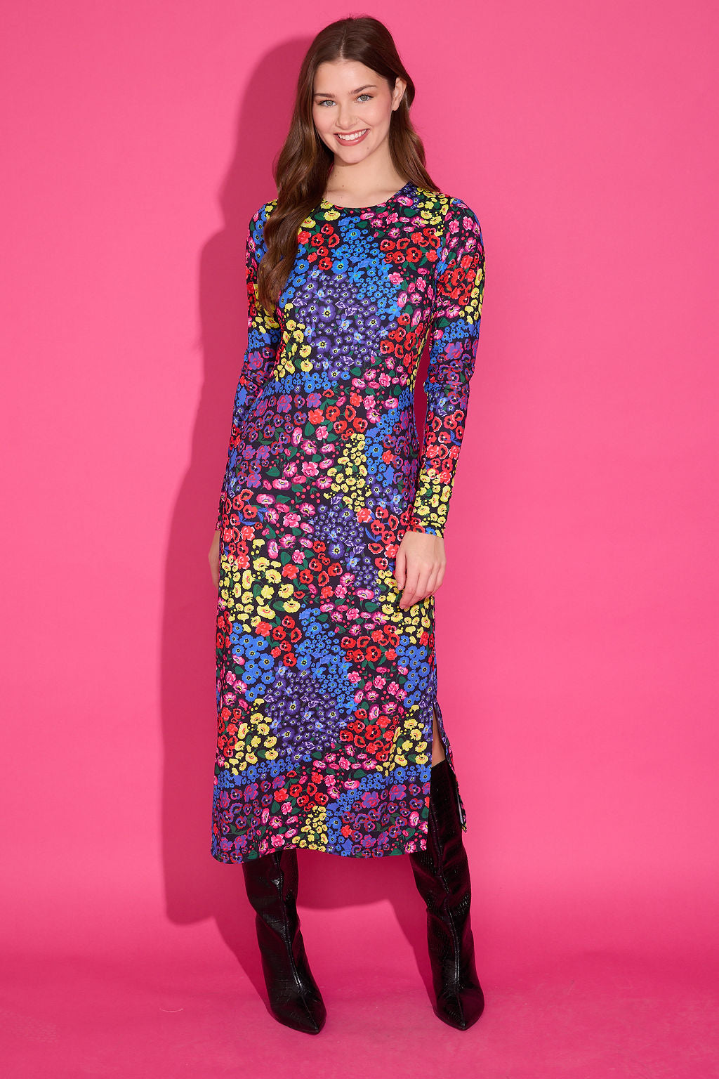 Woman wearing a colorful patterned dress against a pink background