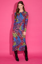 Woman wearing a colorful patterned dress against a pink background