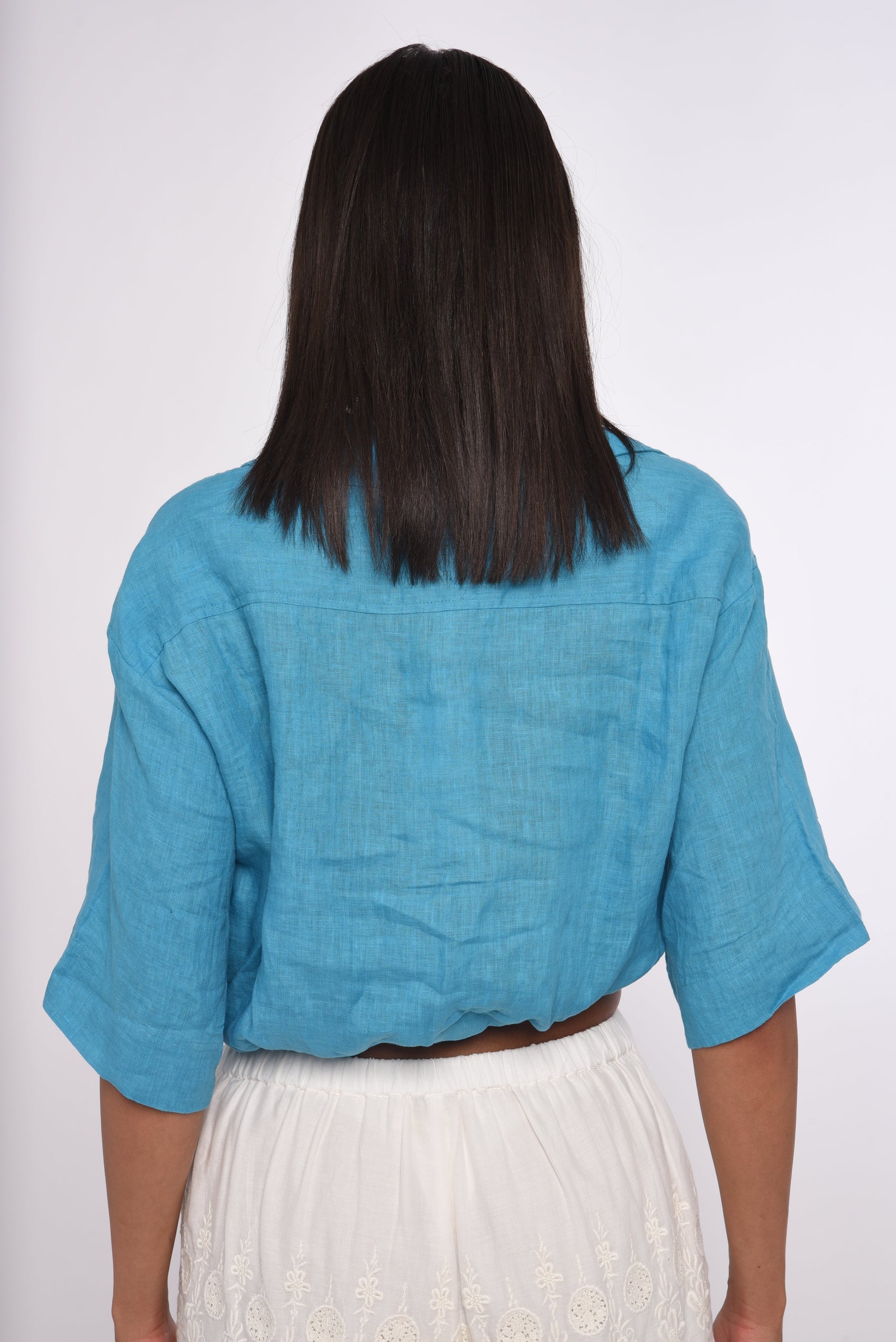 Person wearing a blue top and white pants on a plain background