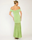 Woman wearing a light green off-shoulder dress with a plain background