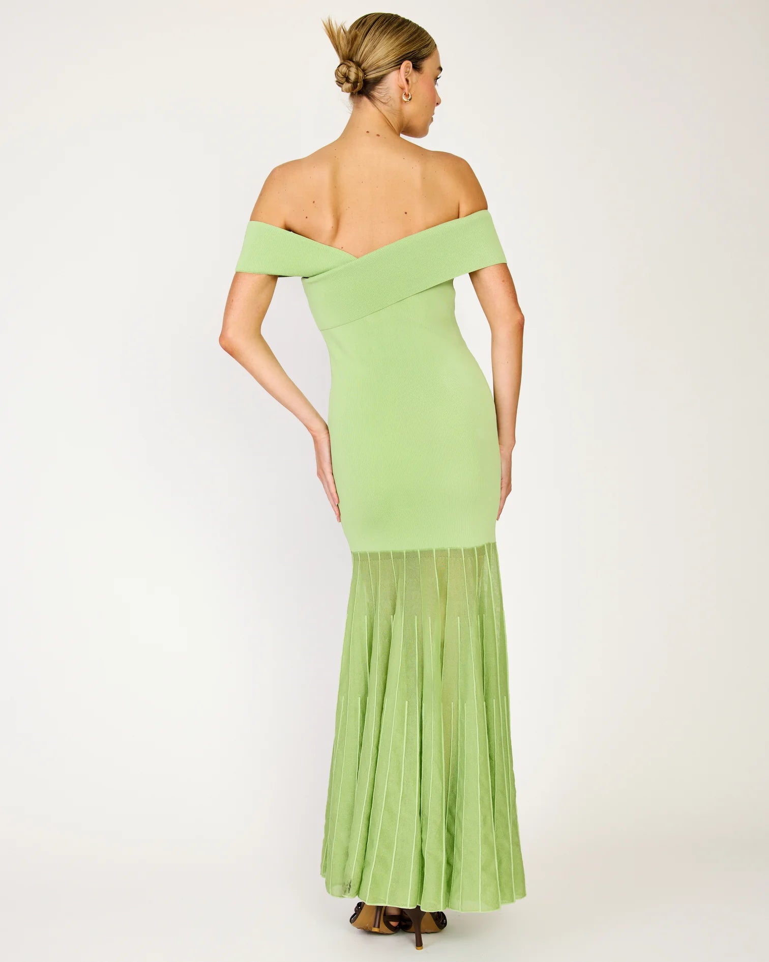 Woman wearing a light green off-shoulder dress with a plain background