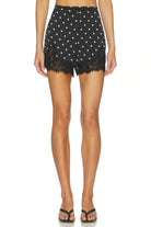 Black lace shorts with white polka dots worn by a person on a white background