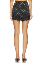 Black polka dot shorts with lace trim worn by a person on a white background