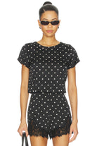 Woman wearing a black polka dot outfit with sunglasses on a white background