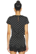 Black polka dot dress with lace hem on a white background