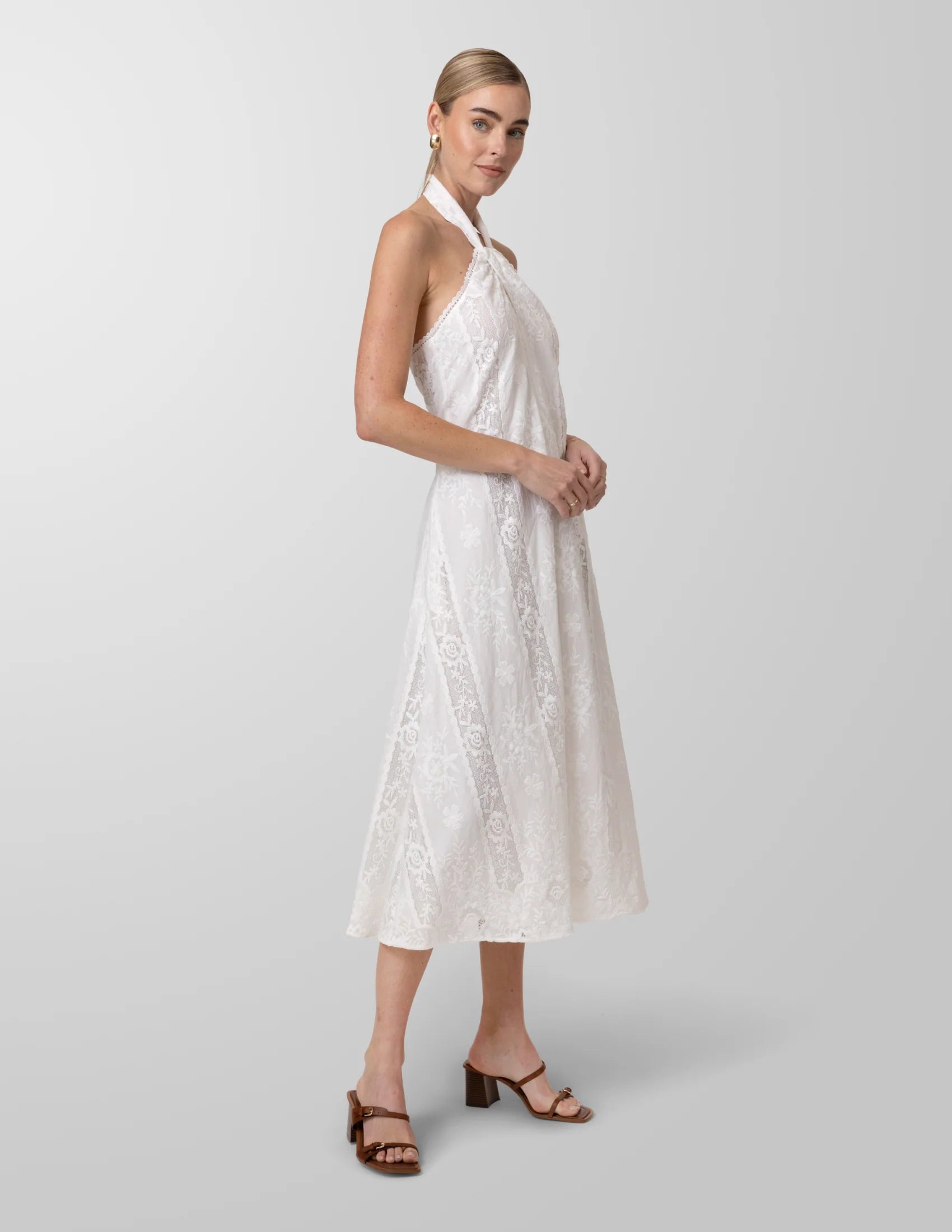 Woman wearing a white halter neck dress on a plain background
