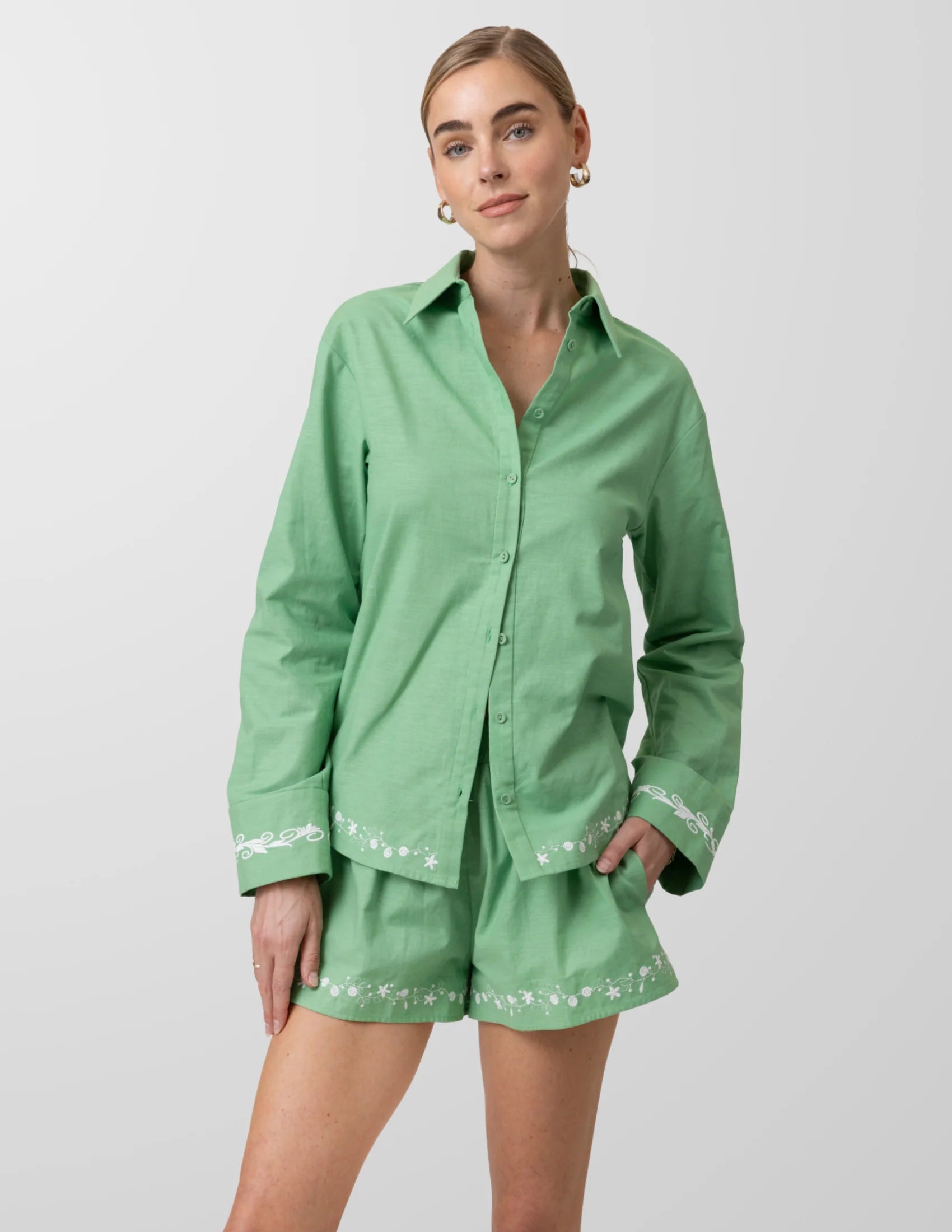 Woman wearing a green outfit with embroidered details on a white background
