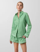 Woman wearing a green outfit with white embroidery on a light gray background