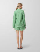 Person wearing a green outfit with white embroidery on a plain background