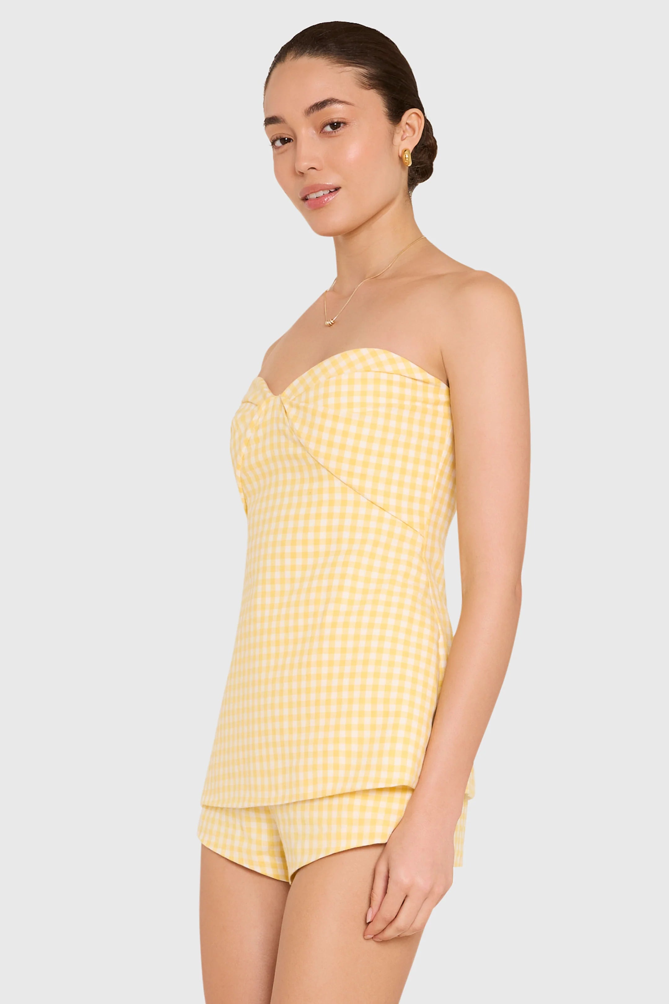Woman wearing a yellow strapless top and shorts set on a white background