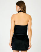 A woman shown from the back wearing a black top against a grey wall