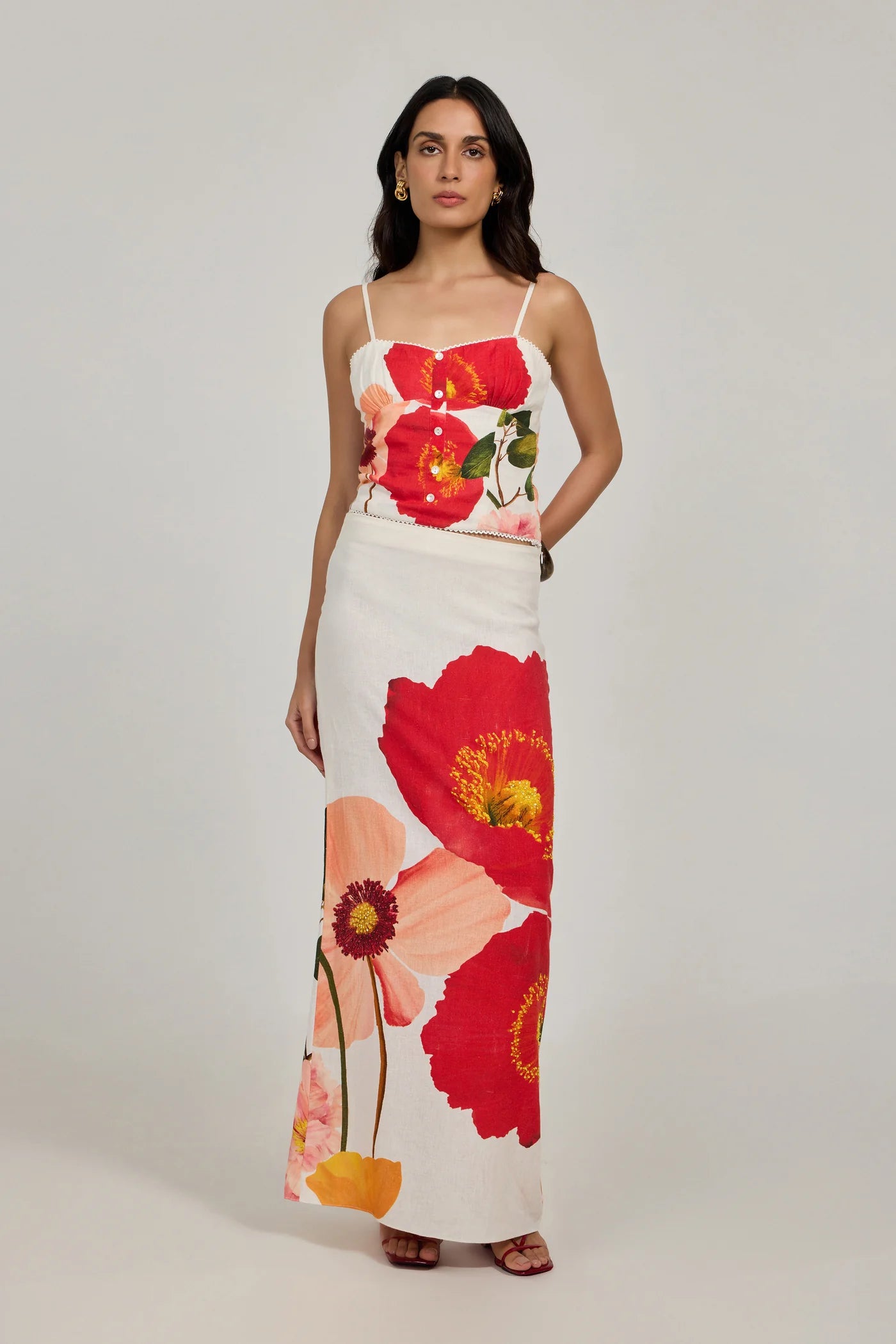 Woman wearing a floral dress with red and pink flowers on a plain background