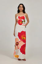 Woman wearing a floral dress with red and pink flowers on a plain background