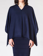 Navy blue poncho worn by a person on a white background