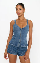 Woman wearing a denim top and shorts on a white background