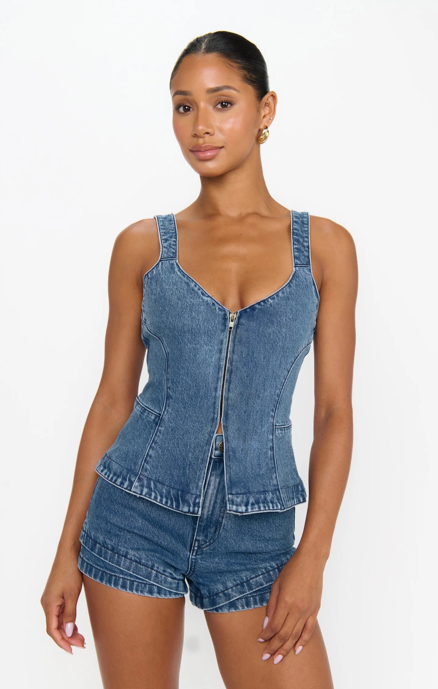 Woman wearing a denim top and shorts on a white background