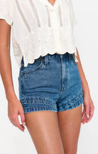Person wearing a white lace top and blue denim shorts on a white background