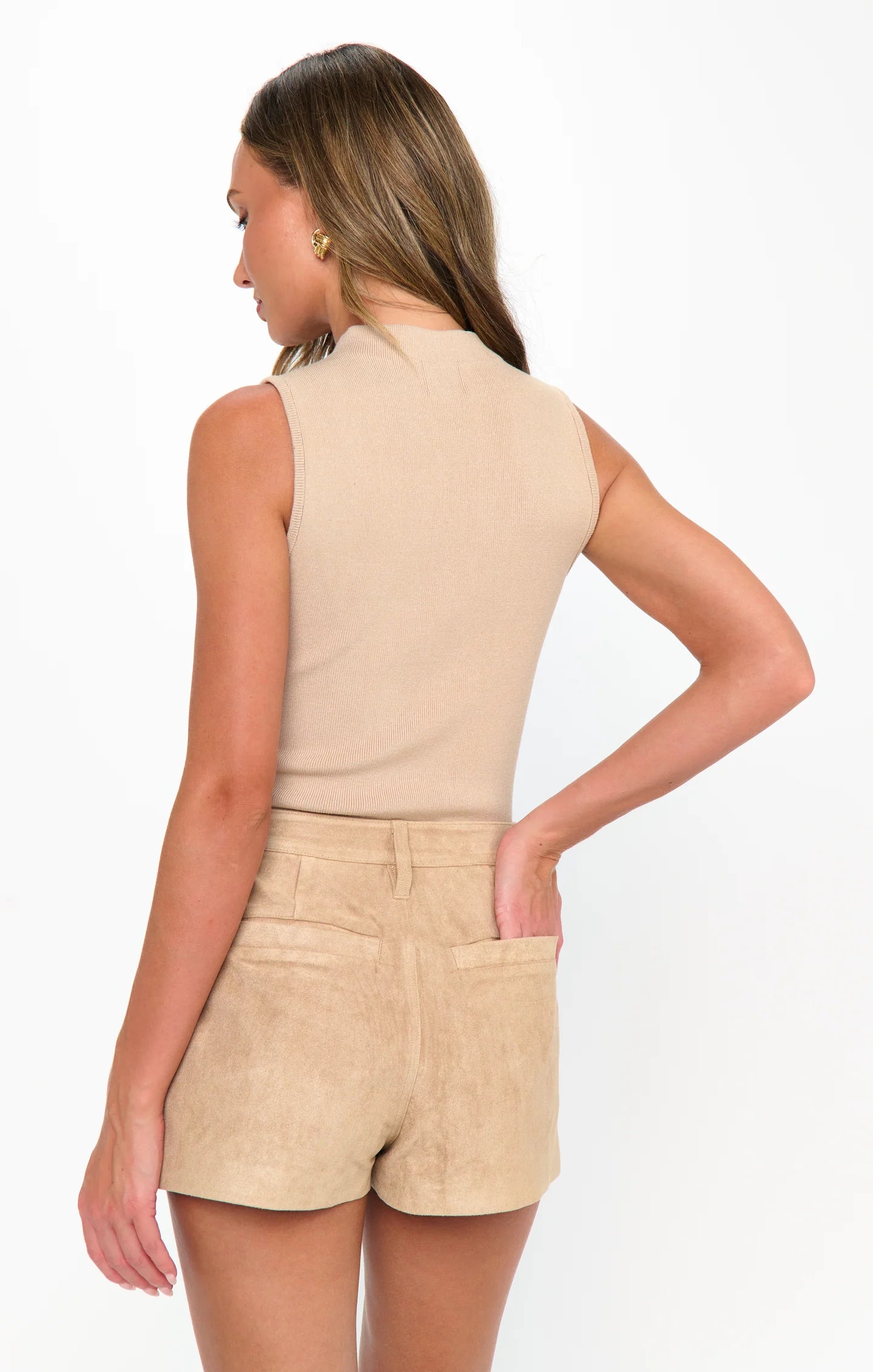 Woman wearing a beige sleeveless top and shorts on a white background