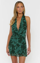 Woman wearing a green printed dress on a white background