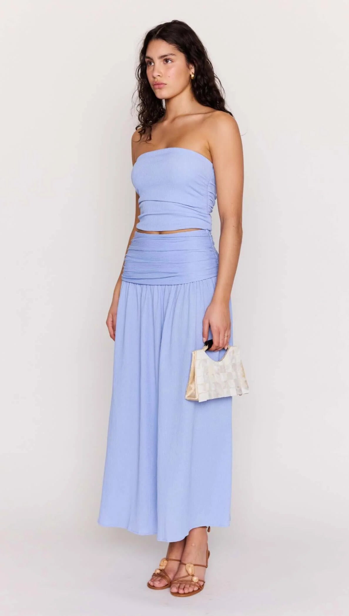 Woman wearing a light blue strapless top and skirt in a bright room.