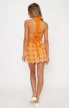 Woman wearing an orange dress with a pattern on a white background