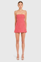 Woman wearing a red checkered strapless dress on a white background