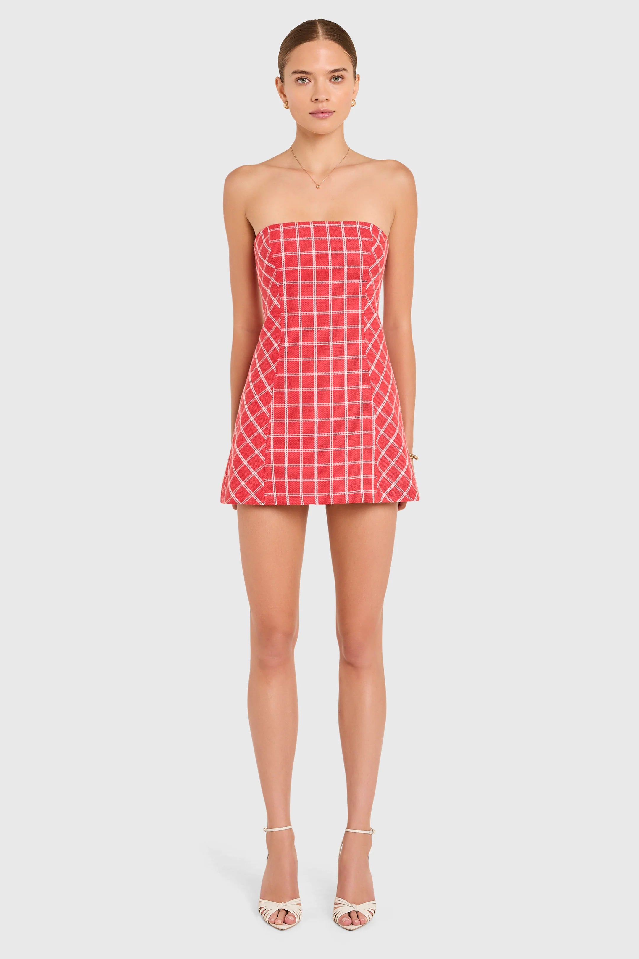 Woman wearing a red checkered strapless dress on a white background