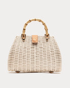 Wicker handbag with gold handle and clasp on a light gray background