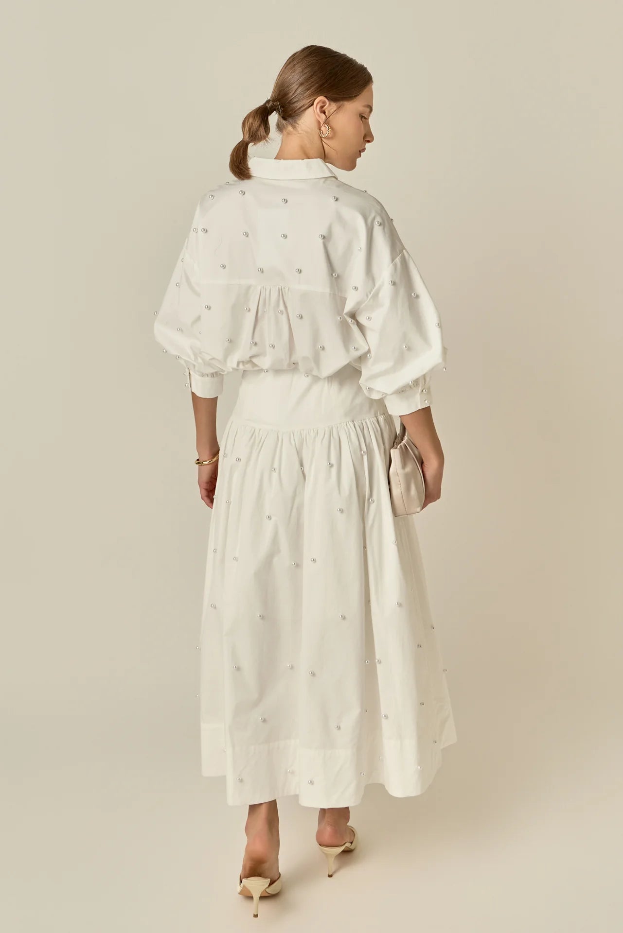 Woman wearing a white dress with a subtle pattern on a beige background
