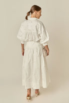 Woman wearing a white dress with a subtle pattern on a beige background