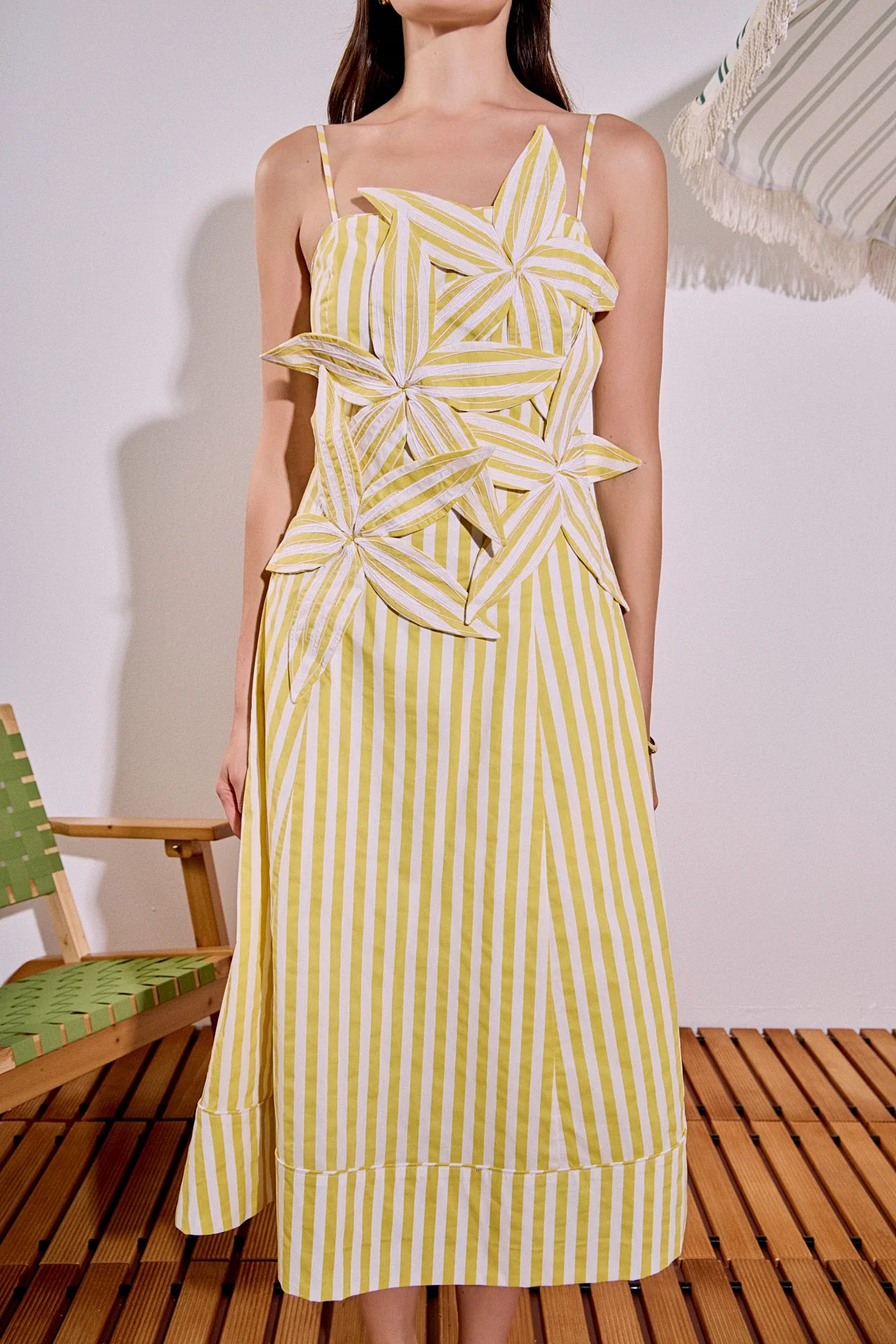 Woman wearing a yellow and white striped dress with star-shaped cutouts on a wooden floor.