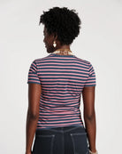 Person wearing a striped shirt with pink and blue horizontal stripes on a plain background