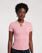 Woman wearing a pink and white striped shirt with a necklace on a plain background