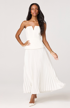 Woman wearing a white strapless dress with pleated skirt on a white background