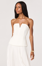 Woman wearing a strapless white dress against a plain background