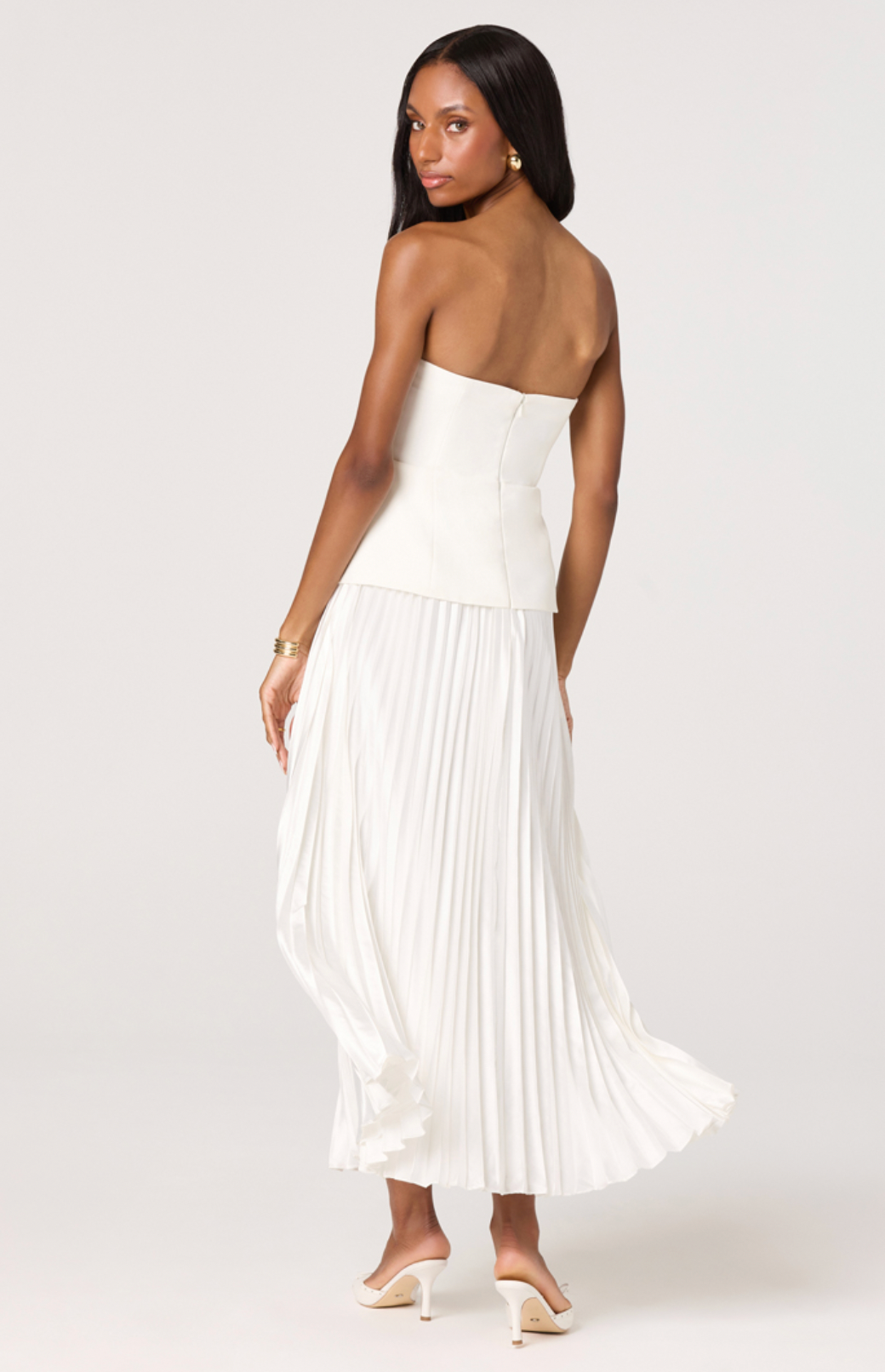 Woman wearing a white strapless pleated dress on a white background